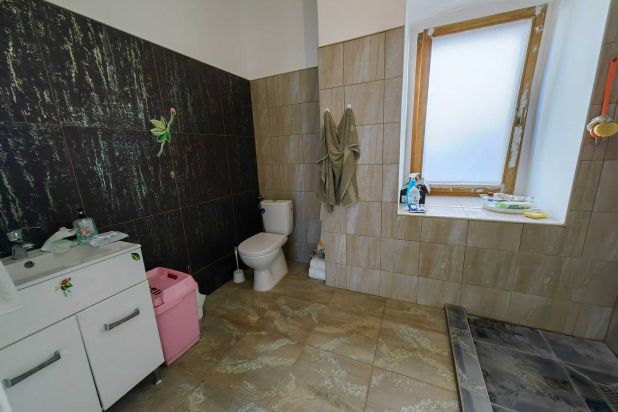 A képen, a fürdőszoba (mosdó,- WC,- épített zuhanyozó) látható.